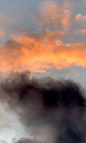 photograph of an orange cloud amidst dark rainy clouds