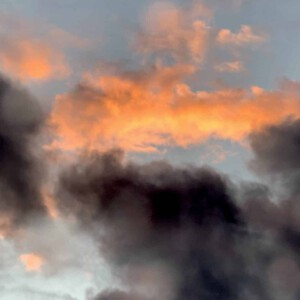 photograph of an orange cloud amidst dark rainy clouds