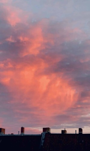 photograph of an oramge cloud lit by sunrise over the roofs of Berlin